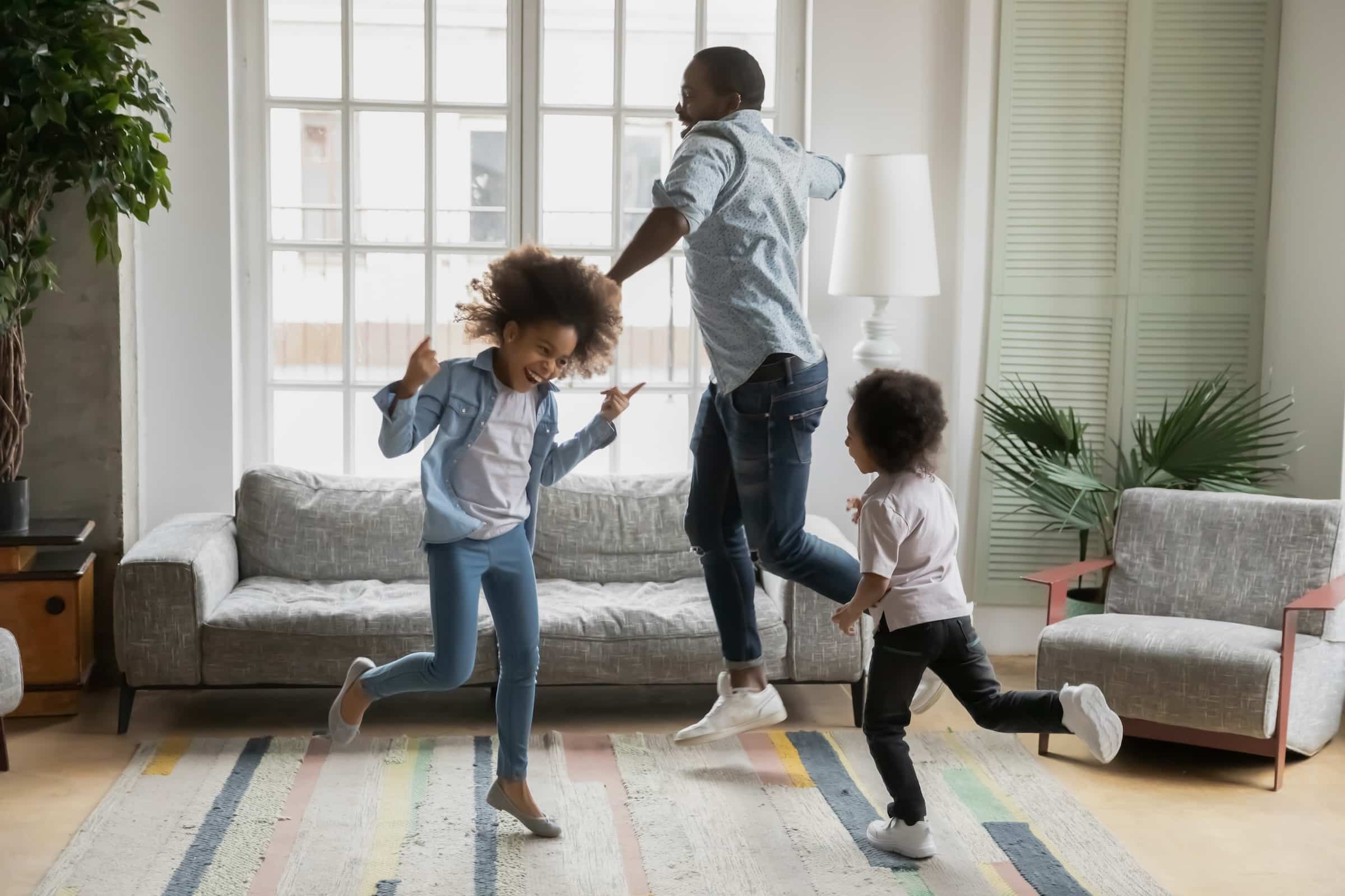 Happy father and kids dancing around a living room