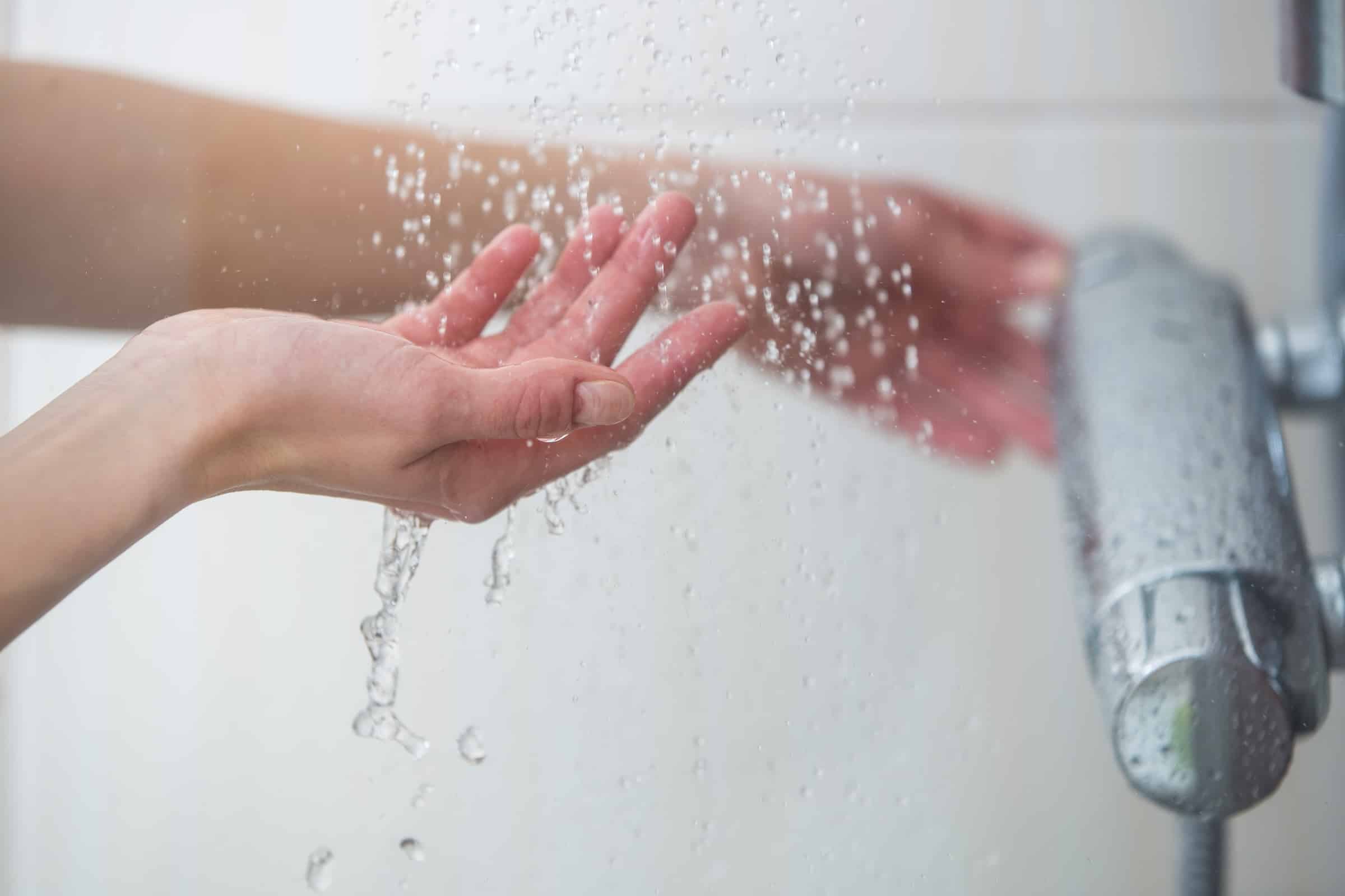 Woman's hands feeling hot water in shower