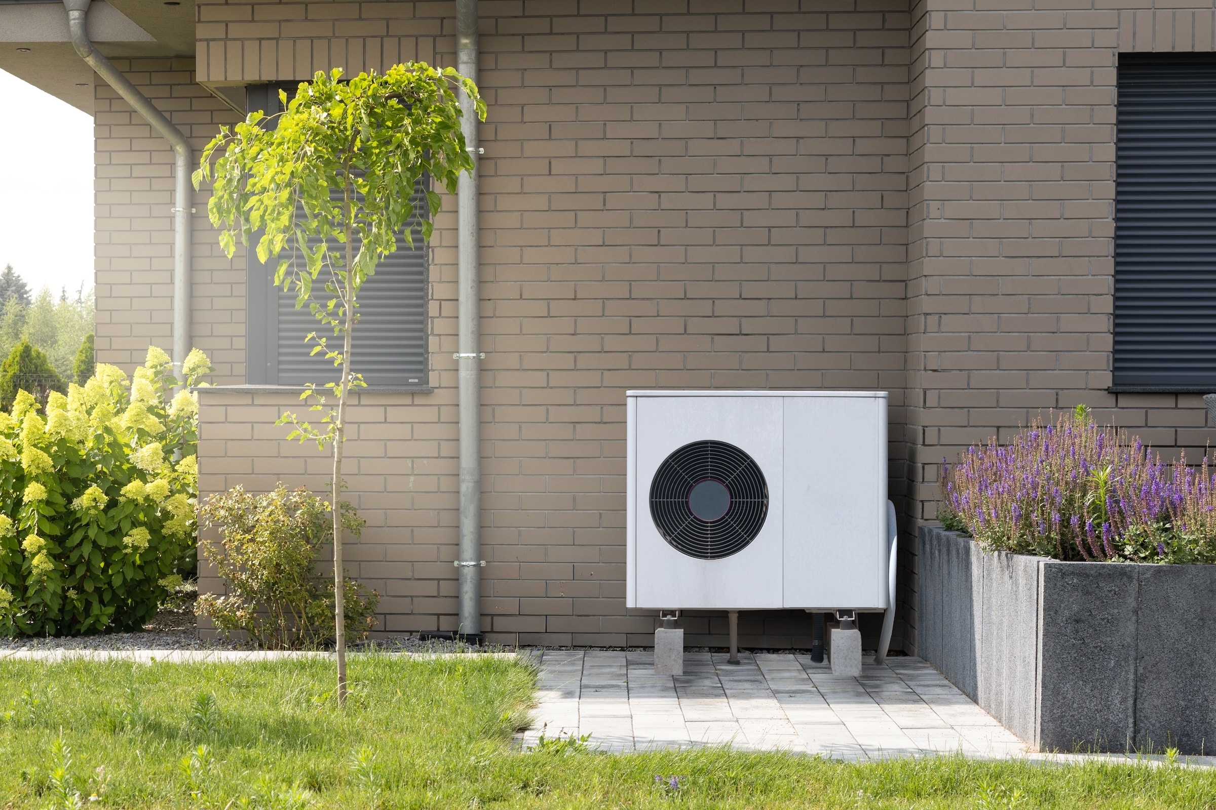 Heat Pump On The Outside Of A House With Green Lawn And Trees