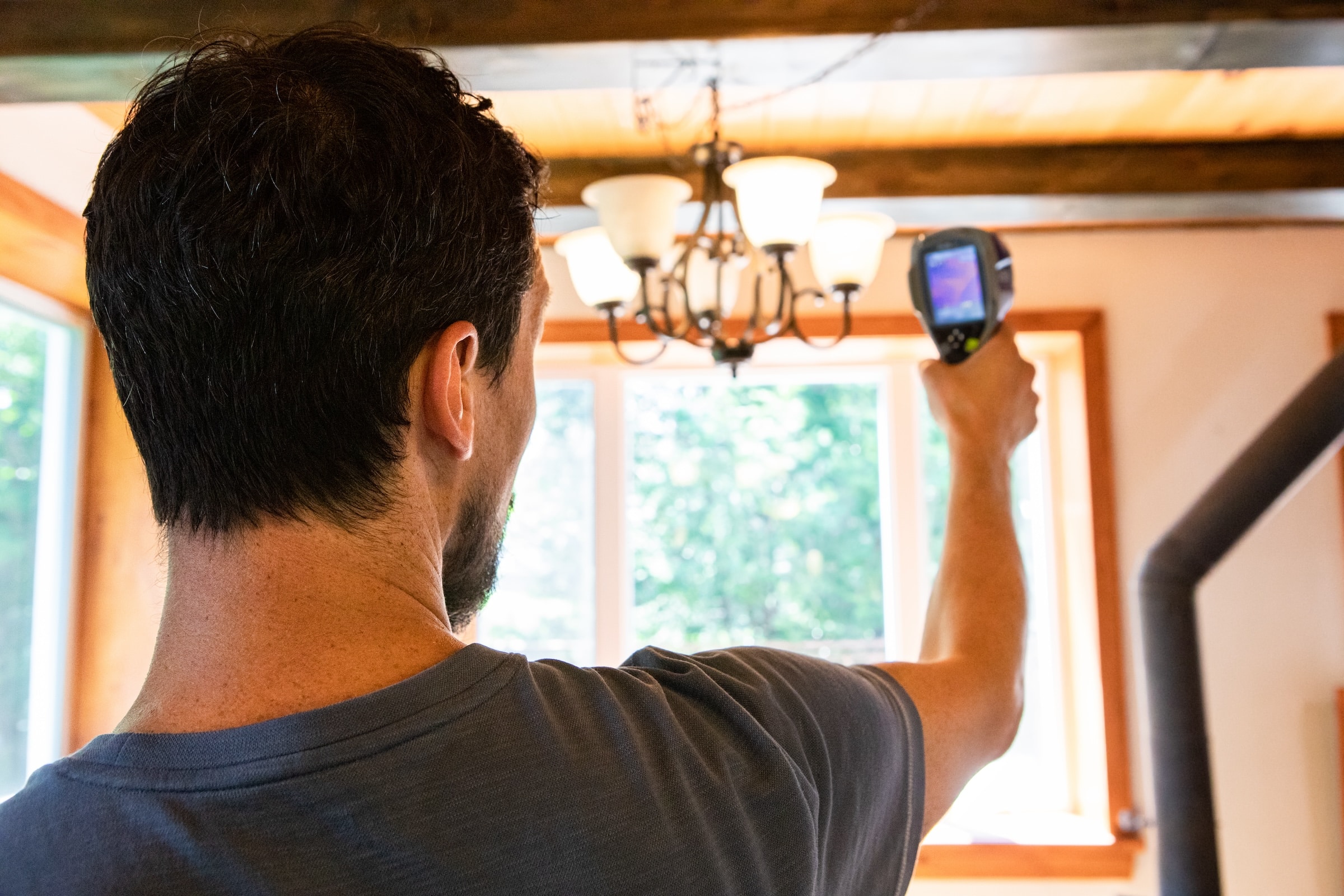 Person using a thermal imaging camera in house to detect air leaks