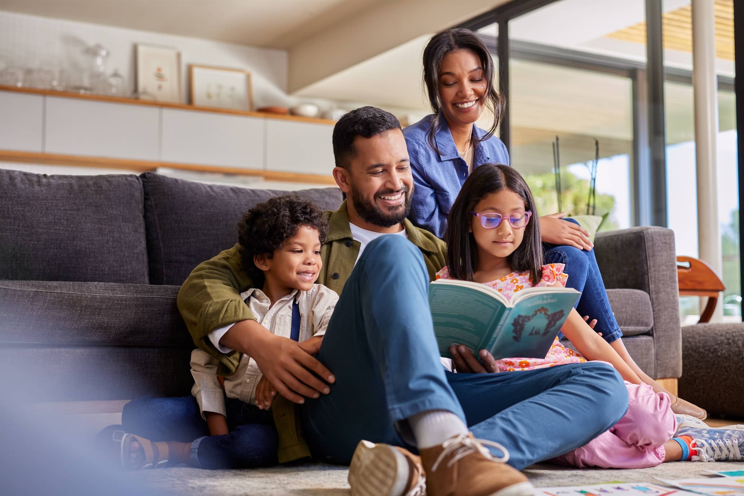Happy family sitting together on the floor of their living room reading a book